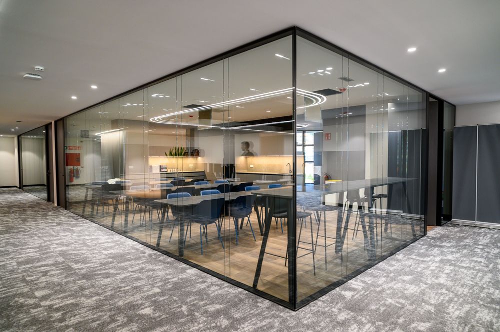 Sala acristalada en esquina con office y mesas de reunión en las oficinas de Sibelco en el edificio Bami, Bilbao