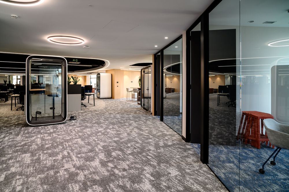 Zona de trabajo abierto con cabina acústica y mamparas de vidrio en las oficinas reformadas de Sibelco, Bilbao