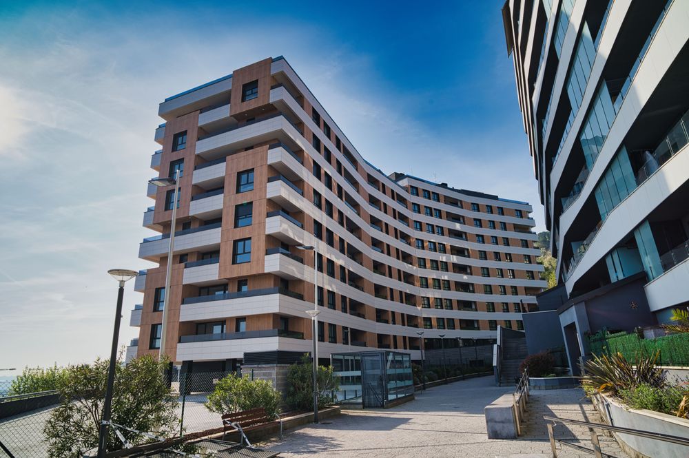 Curved-facade residential building in white and wood of the 89 homes in Santurtzi, seen from the street