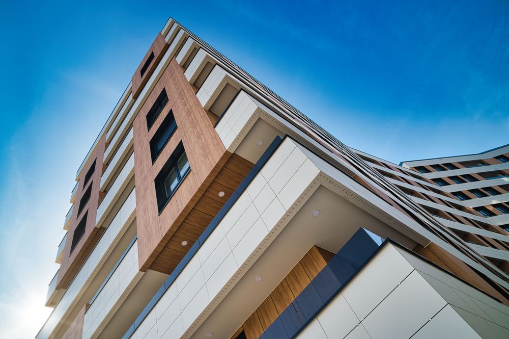 Low-angle view of the facade of the 89 homes in Santurtzi above the entrance, with white eaves and wood cladding