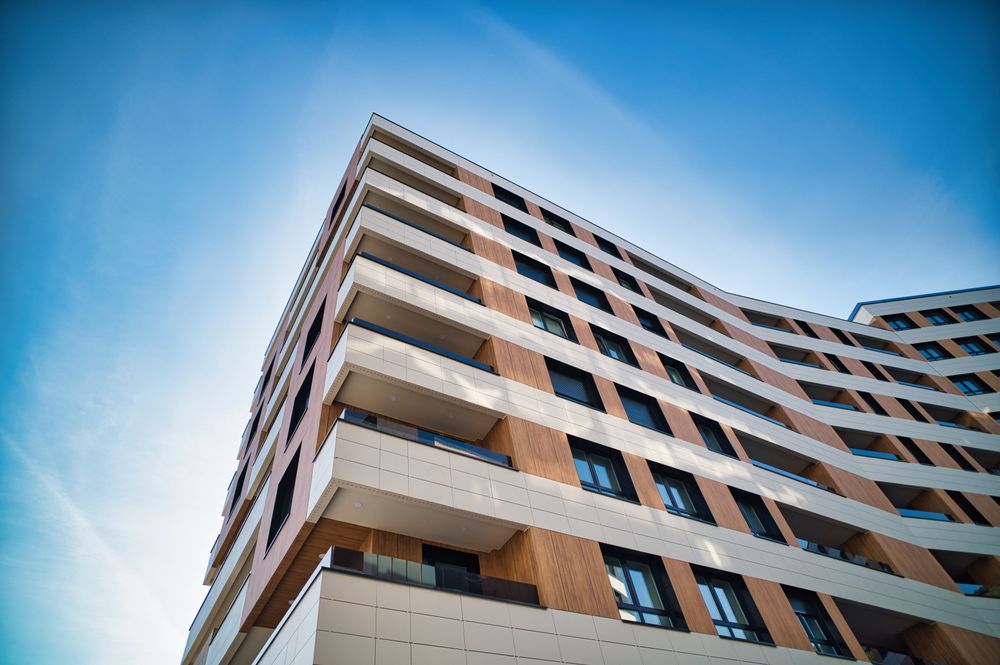 Low-angle corner view of the Santurtzi building, with cantilevered terraces in white bands and wood panels
