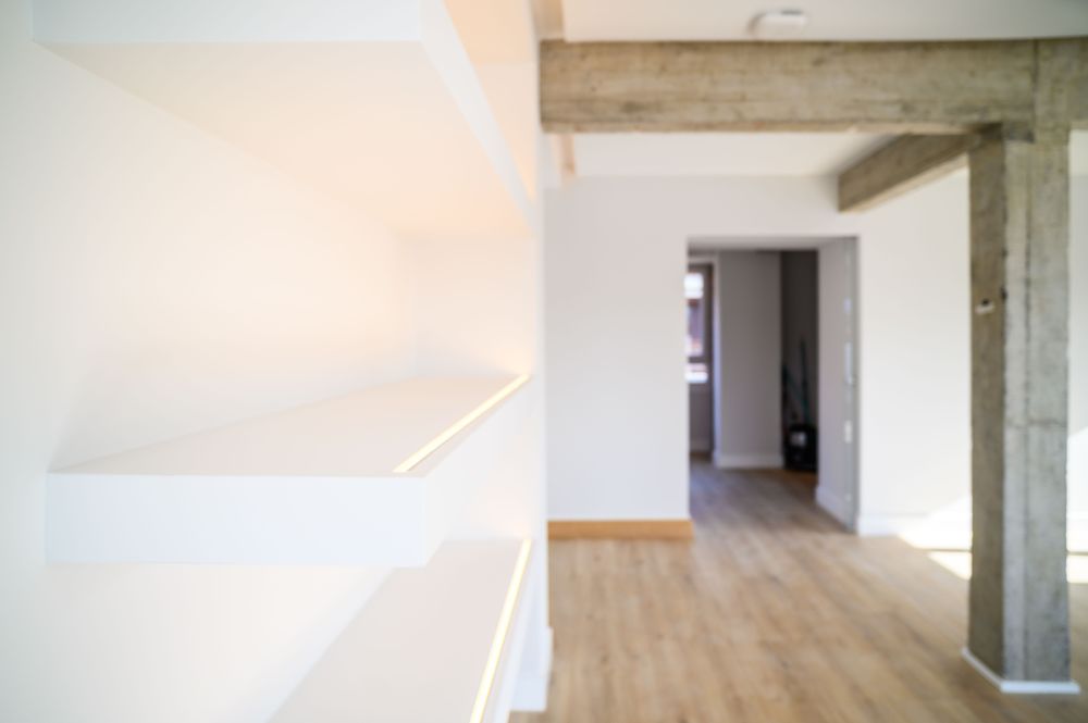 White shelves with LED lighting and exposed concrete structure in the home in Jaureguialde