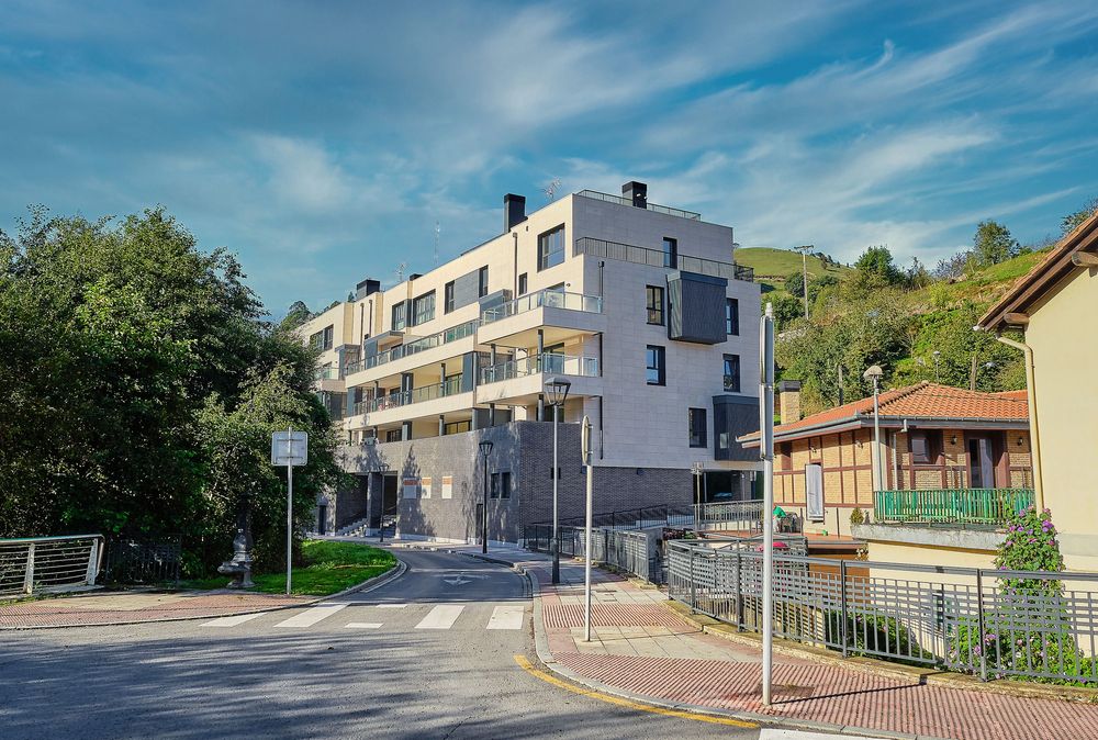 Facade of the Gorostiza Loft building in Barakaldo, with trees in the foreground and the mountain in the background