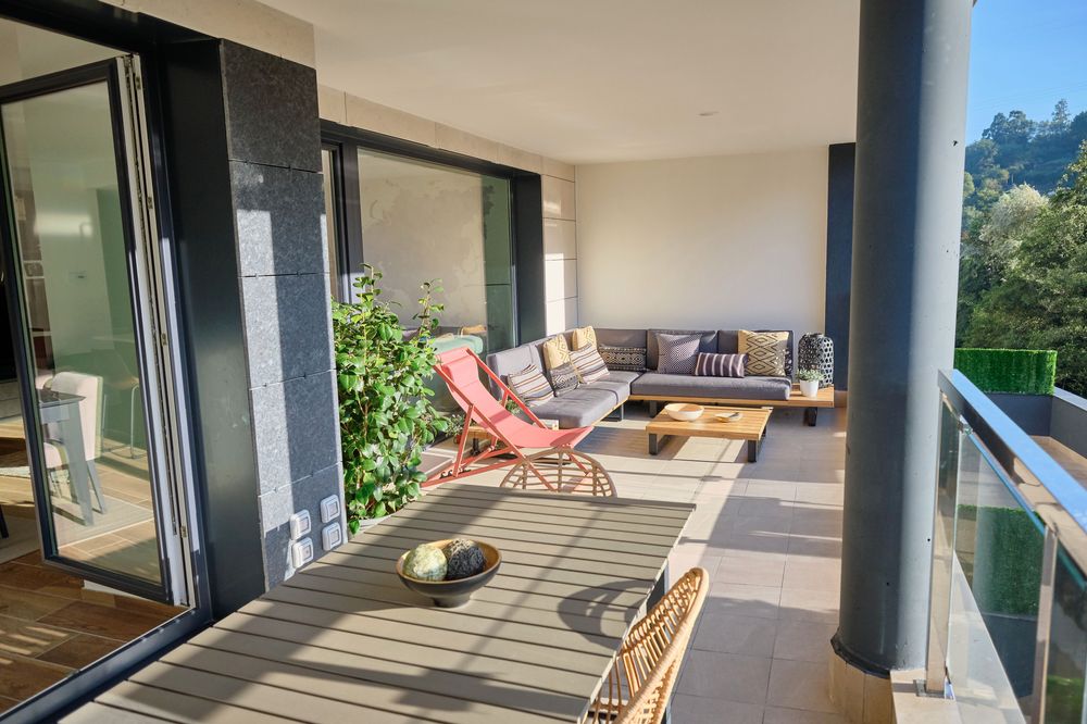 Terrace of a Gorostiza Loft home with a dining table, sofas, and views of the wooded valley