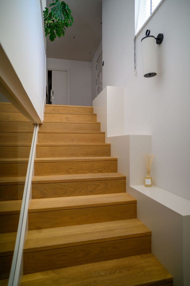 Oak staircase with a wall sconce in the renovated home in Neguri, Getxo