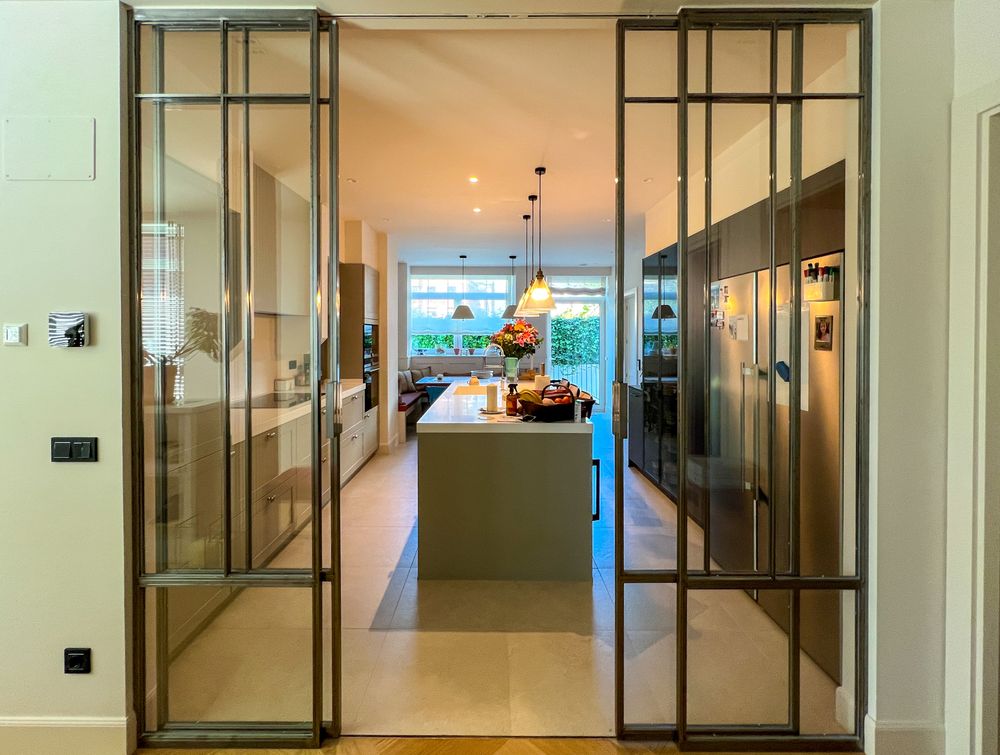 Glazed sliding doors with metal frames opening onto the island kitchen in the Neguri home