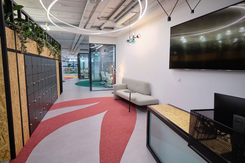 Reception of the Smartgrid Innovation Hub with a gray sofa, lockers, a screen, and a floor decorated in red and white