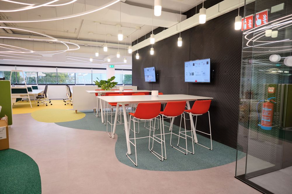 High tables with red stools next to a black wall with screens at the Iberdrola Smartgrid Innovation Hub