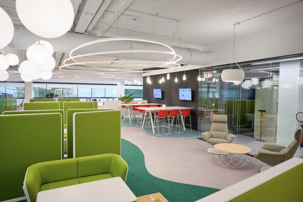 Work area of the Smartgrid Innovation Hub with green panels, circular light fixtures, and high tables with red stools