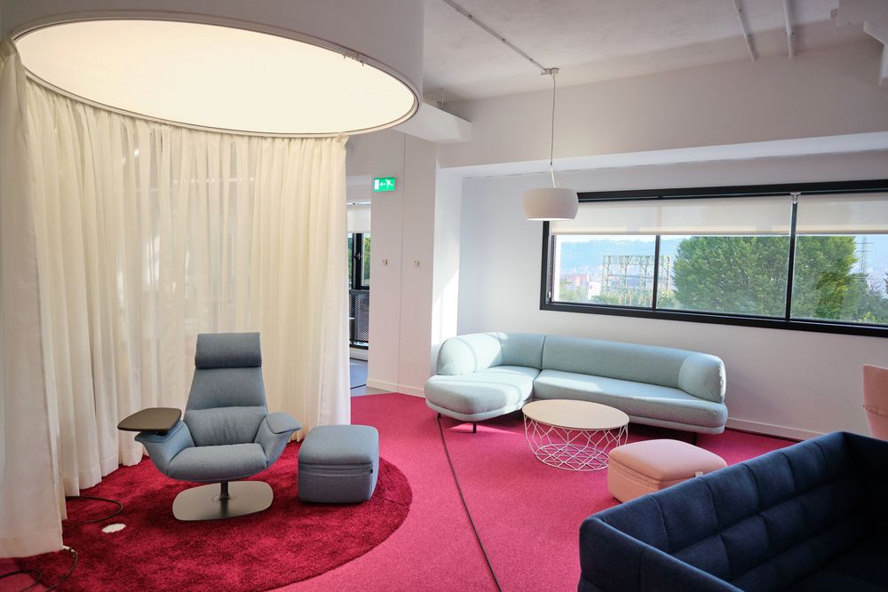 Rest area with red carpet, sofas in blue tones, and a white circular curtain at the Smartgrid Innovation Hub